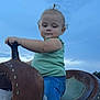 Hadley is registered to the contest to win money with this photo: child, toddler, saddle, horse_riding, outdoor, blue_sky, jeans, green_shirt, hand, nail_polish, curly_hair, rustic, leather, seat, person, holding, grip, calm, casual_clothing, nature