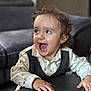 Nathéo participe au concours pour gagner de l'argent avec cette photo : toddler, child, smiling, happy, curly_hair, indoor, table, vest, shirt, face, hands, couch, furniture, expression, portrait, young_child, playing, cute, person, home