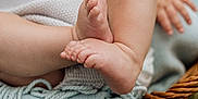 Halston is registered to the contest to win money with this photo: baby, legs, feet, blanket, woven_basket, grass, outdoor, soft_texture, fringes, skin, close_up, resting, candid, natural_light, infant, cute, fingers, toes, blurred_background, cozy
