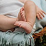 baby, legs, feet, blanket, woven_basket, grass, outdoor, soft_texture, fringes, skin, close_up, resting, candid, natural_light, infant, cute, fingers, toes, blurred_background, cozy