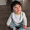 Natalie joined the competition — help win amazing prizes! toddler, baby, child, sitting, floor, wooden_floor, bib, striped_shirt, pants, socks, indoor, person, cute, young_child, looking_up, curious, expression, hair, face, hands