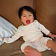 Natalie joined the competition — help win amazing prizes! baby, child, pajamas, smiling, laughing, face, foot, couch, pillow, indoor, person, cute, happy, young_child, home, infant, cozy, relaxed, clothing, portrait