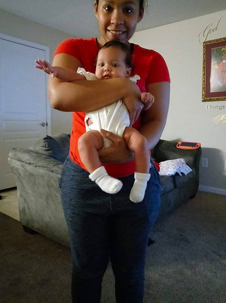Jamaica is registered to the contest to win money with this photo: arm, baby, comfort, gesture, happy, human_body, interaction, jeans, joint, joy, knee, lap, leg, person, picture_frame, shoulder, smile, standing, t_shirt, thigh