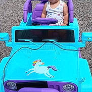 Mary is registered to the contest to win money with this photo: baby, car, clothing, face, fun, grass, head, machine, nature, outdoors, person, photography, plant, portrait, purple, summer, t_shirt, transportation, vehicle, wheel