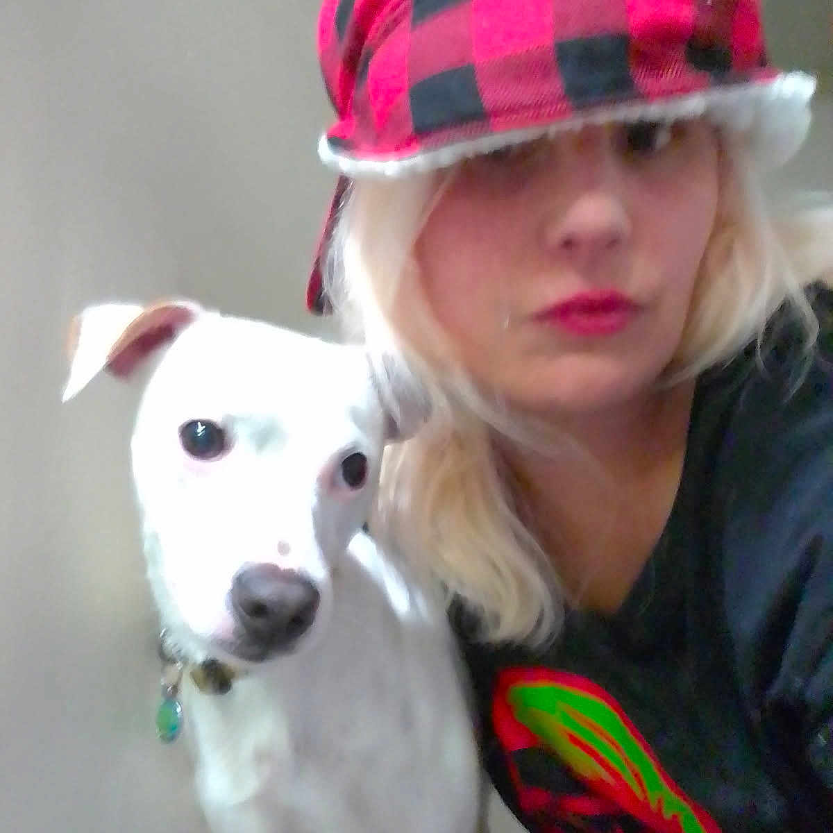 Lucki joined the competition — help win amazing prizes! animal, black_shirt, blonde_hair, candid, casual, close_up, collar, companion, dog, friendship, hat, indoor, looking_at_camera, person, pet, plain_background, portrait, red_and_black_hat, soft_lighting, white_dog