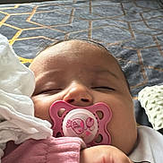 Naya is registered to the contest to win money with this photo: baby, pacifier, sleeping, hand, clothing, bedspread, blanket, indoor, cozy, infant, face, peaceful, child, resting, cute, person, pink, soft, home, portrait