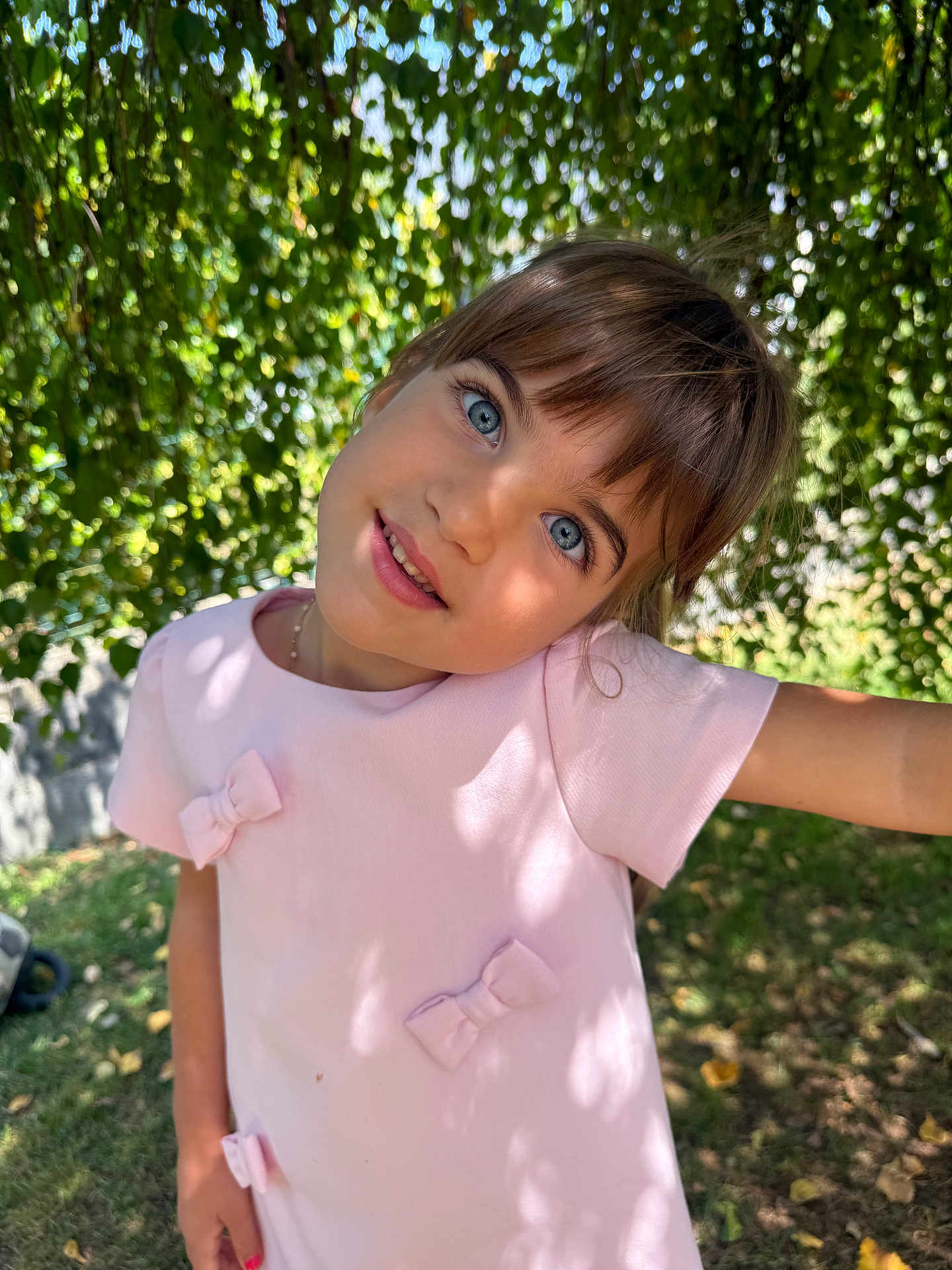 Giulia a rejoint le concours — aidez-le/la à gagner de superbes lots ! child, girl, blue_eyes, pink_dress, bows, outdoor, nature, greenery, sunlight, shadow, smile, portrait, happy, cute, young, face, grass, tree, leaves, playful