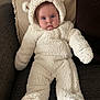 baby, child, infant, white, bear_costume, fluffy, onesie, hood, ears, blue_eyes, couch, pillow, beige, soft_texture, warm_clothing, indoors, portrait, cute, seated, cozy