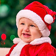 Eithan joined the competition — help win amazing prizes! baby, child, santa_hat, christmas, holiday, red_clothing, white_fur, smile, happy, portrait, festive, cute, face, closeup, indoors, celebration, seasonal, costume, background_blur, colorful_lights