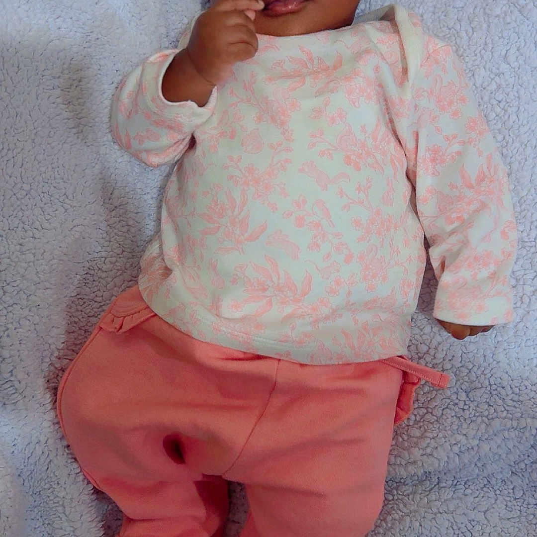 Jesulayomi is registered to the contest to win money with this photo: baby, blanket, child, closeup, cozy, curious, cute, floral_top, hand_near_mouth, indoors, infant, lying_down, person, pink_pants, portrait, skin, sleepwear, soft_texture, wide_eyes, young