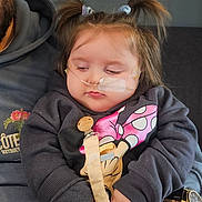 Ellthea is registered to the contest to win money with this photo: toddler, child, pigtails, nasal_cannula, sweatshirt, minnie_mouse, pacifier, hand, tattoo, watch, adult, lap, clothing, face, person, indoor, resting, cute, pink_pants, holding