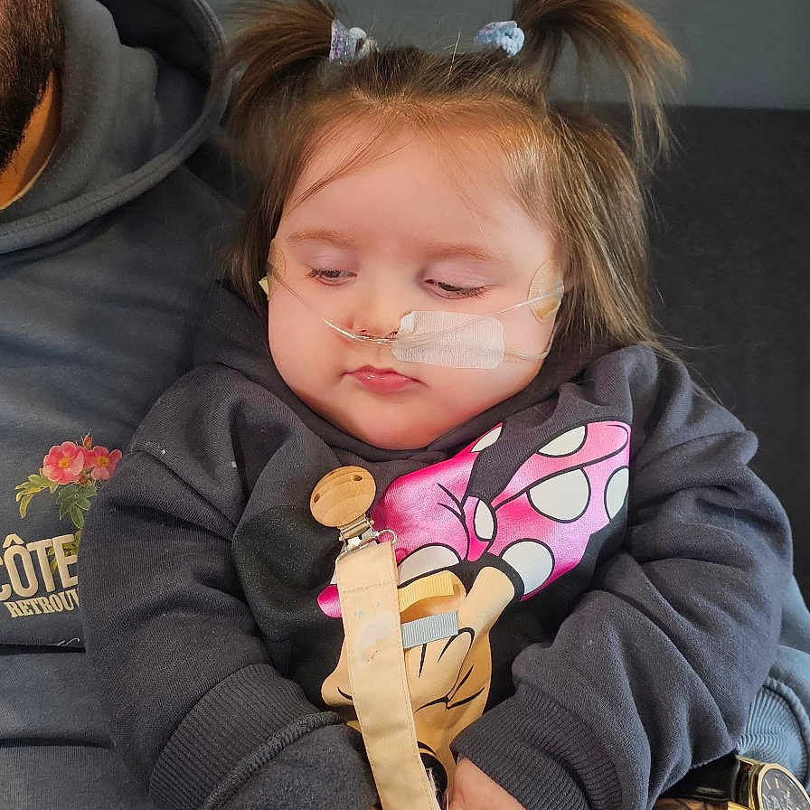 Ellthea is registered to the contest to win money with this photo: adult, child, clothing, cute, face, hand, holding, indoor, lap, minnie_mouse, nasal_cannula, pacifier, person, pigtails, pink_pants, resting, sweatshirt, tattoo, toddler, watch