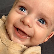 Denis a rejoint le concours — aidez-le/la à gagner de superbes lots ! baby, smile, face, blue_eyes, close_up, infant, cute, happy, child, portrait, cozy, soft_texture, beige_clothing, ear_detail, skin, young_child, expression, joyful, indoors, warm