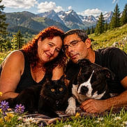 Tyna participe au concours pour gagner de l'argent avec cette photo : couple, woman, man, black_cat, dog, outdoor, mountains, wildflowers, nature, smiling, glasses, blanket, grass, sunlight, portrait, pets, relaxing, scenic, happy, summer