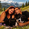 couple, woman, man, black_cat, dog, outdoor, mountains, wildflowers, nature, smiling, glasses, blanket, grass, sunlight, portrait, pets, relaxing, scenic, happy, summer