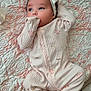 baby, infant, onesie, headband, blanket, quilt, pattern, pink, white, face, hand, footed_pajamas, cute, sleepwear, child, lying_down, tattoo, skin, cozy, soft