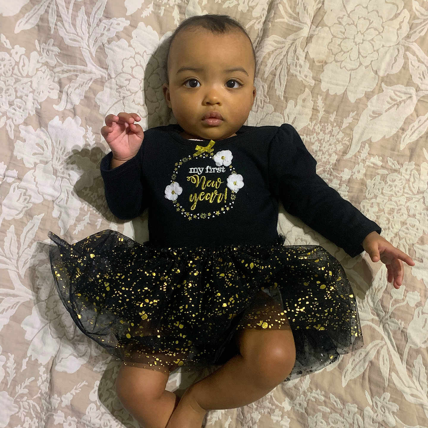 Rosalina joined the competition — help win amazing prizes! baby, infant, child, black_clothing, sparkles, tutu_skirt, bedspread, floral_pattern, lying_down, barefoot, curious_expression, raised_hand, indoors, portrait, cute, festive, new_year, celebration, young, person