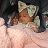 baby, infant, car_seat, blanket, pink, bow, sleeping, child, face, clothing, floral, cute, soft, comfort, resting, young, person, toddler, indoors, peaceful