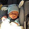 newborn, baby, infant, child, car_seat, vehicle, hat, winged_hat, blanket, clothing, sleepy, face, portrait, seated, safety_harness, sunlight, indoor, travel, infant_carrier, photography