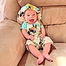 baby, smile, happy, mickey_mouse, hat, clothing, infant, sitting, couch, furniture, face, person, cute, child, indoors, apparel, joy, relaxing, comfort, portrait