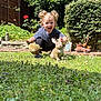 toddler, child, garden, grass, plants, flowers, statues, rabbit_statues, greenery, sunlight, happy, curly_hair, outdoor, crouching, playful, decorations, nature, smiling, blue_shirt, black_pants