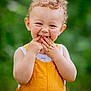 Mayron a rejoint le concours — aidez-le/la à gagner de superbes lots ! toddler, child, smile, curly_hair, orange_overall, playful, portrait, outdoor, green_background, happy, cute, person, young_child, fun, expression, skin, face, hands, nature, summer