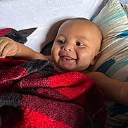 Kyire joined the competition — help win amazing prizes! arm, baby, black, blanket, child, closeup, comfort, cozy, cute, face, happy, head, indoors, infant, lying_down, pillow, red, skin, smiling, tongue_out