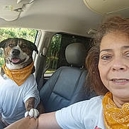 Oso is registered to the contest to win money with this photo: dog, person, woman, selfie, car, vehicle, bandana, shirt, clothing, seated, portrait, face, smiling, outdoors, greenery, road_trip, pet, companion, automobile, daylight