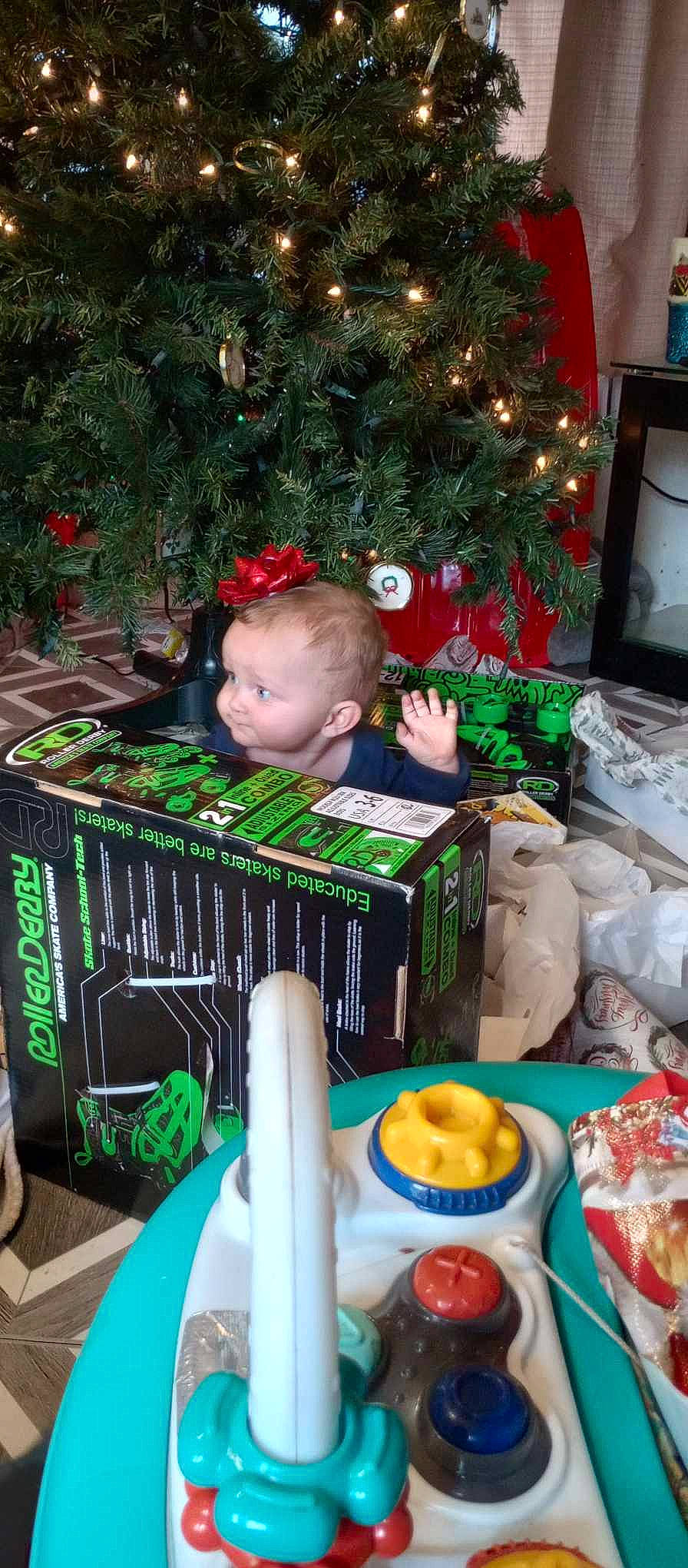 Kanaan is registered to the contest to win money with this photo: box, child, christmas, christmas_decoration, christmas_ornament, christmas_tree, comfort_food, conifer, event, fun, holiday, holiday_ornament, interior_design, natural_foods, ornament, person, room, sweetness, television, toddler