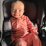 Olivia joined the competition — help win amazing prizes! baby, infant, car_seat, pink_clothing, smile, happy, child, seatbelt, blue_eyes, face, portrait, cute, young_child, clothing, sitting, indoor, headrest, harness, closeup, person