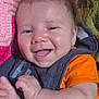 baby, smiling, happy, infant, orange_shirt, bib, pink_blanket, crochet, lying_down, face, hand, skin, hair, expression, child, indoors, closeup, cute, person, portrait