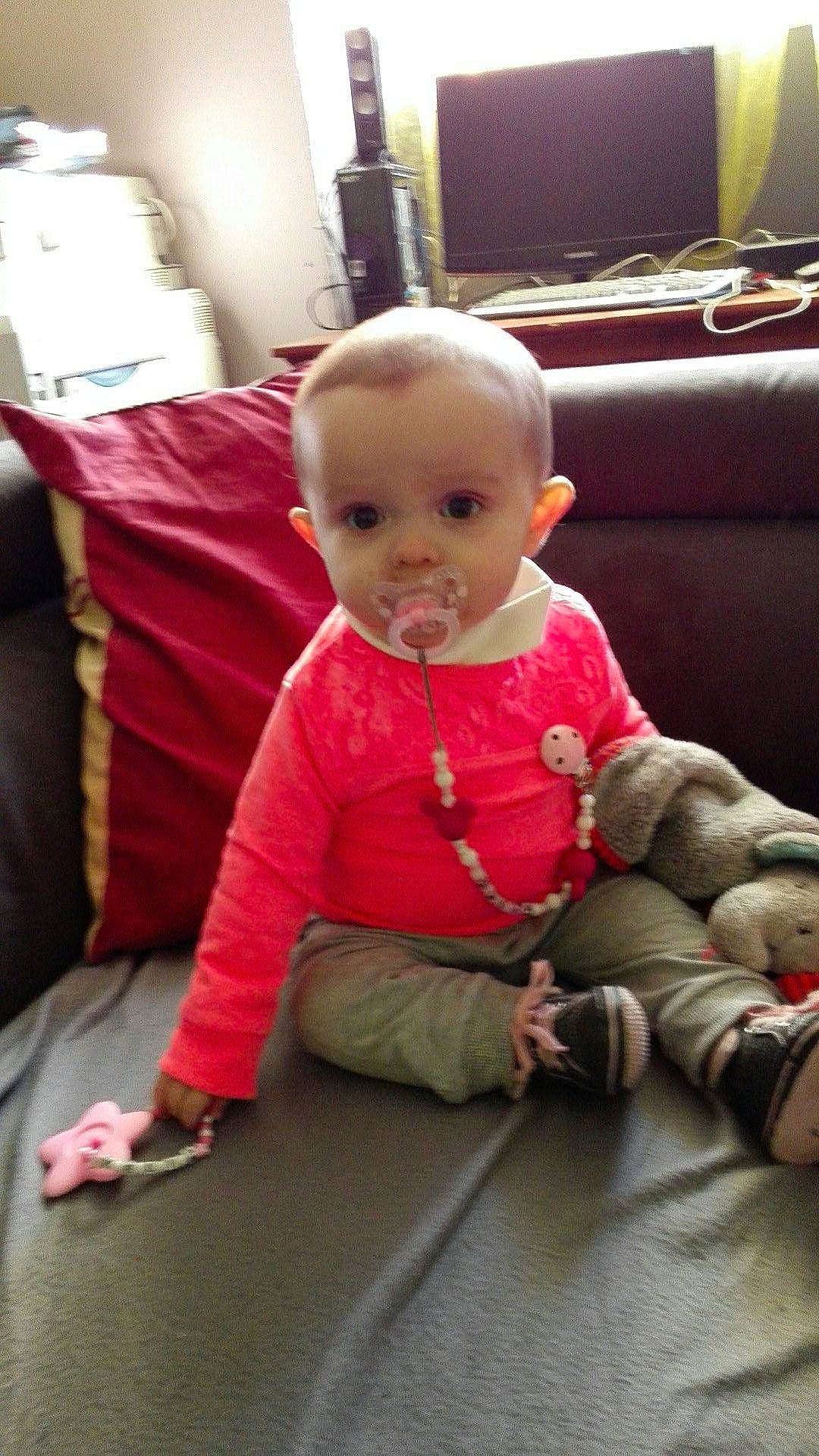 Zélia participe au concours pour gagner de l'argent avec cette photo : child, day, eye, fun, girl, infant, organ, person, pink, play, product, red, sitting, skin, smile, textile, toddler