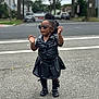 toddler, child, outdoor, street, sunglasses, black_clothing, leather, standing, fashion, confident, shoes, sock, hair, curly_hair, urban, sidewalk, road, trees, daytime, person