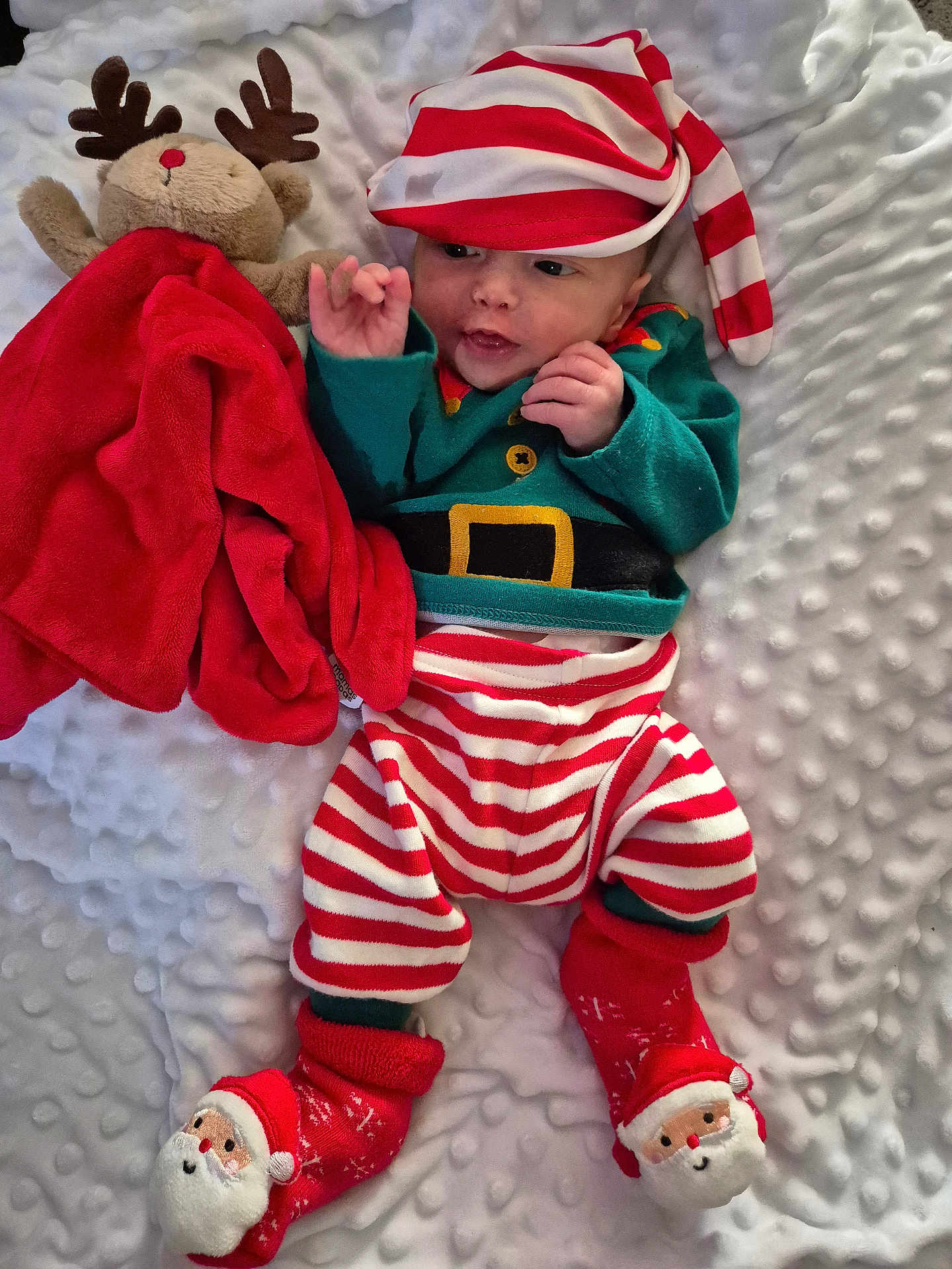 Elijah joined the competition — help win amazing prizes! baby, infant, child, christmas_outfit, striped_clothing, hat, plush_toy, reindeer, blanket, red, white, green, christmas_theme, smiling, cute, lying_down, socks, soft_texture, holiday, festive