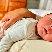 Kenneth is registered to the contest to win money with this photo: baby, sleeping, infant, hand, adult, bedroom, wooden_furniture, cozy, peaceful, rest, closeup, face, skin, clothing, white_shirt, newborn, portrait, comfort, parent, tender_moment