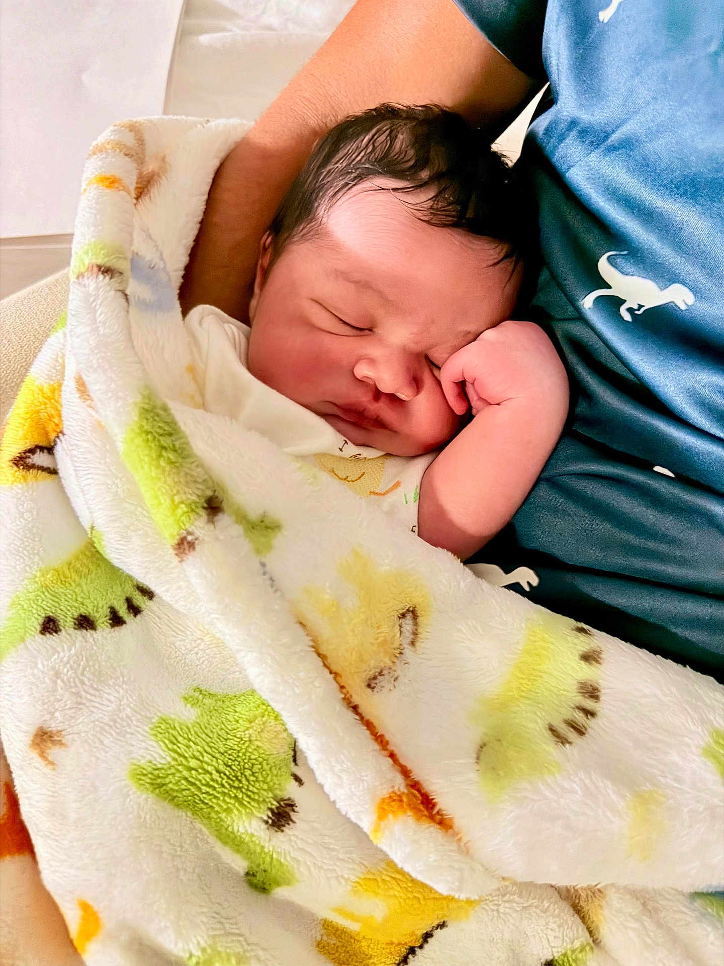 Kenneth joined the competition — help win amazing prizes! newborn, baby, sleeping, blanket, dinosaur_pattern, arm, blue_shirt, infant, soft_texture, peaceful, cute, resting, child, person, portrait, wrapped, cozy, indoor, closeup, toddler