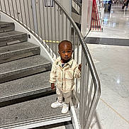 Isaac participe au concours pour gagner de l'argent avec cette photo : toddler, child, stairs, railing, indoor, modern_building, marble_floor, jacket, pants, sneakers, curious, standing, person, urban, metal, handrail, floor, corridor, shopping_mall, casual_clothing