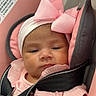 baby, infant, child, pink, headband, bow, car_seat, seat_belt, clothing, portrait, face, straps, soft_toys, cushion, indoors, cute, baby_girl, closeup, expression, resting