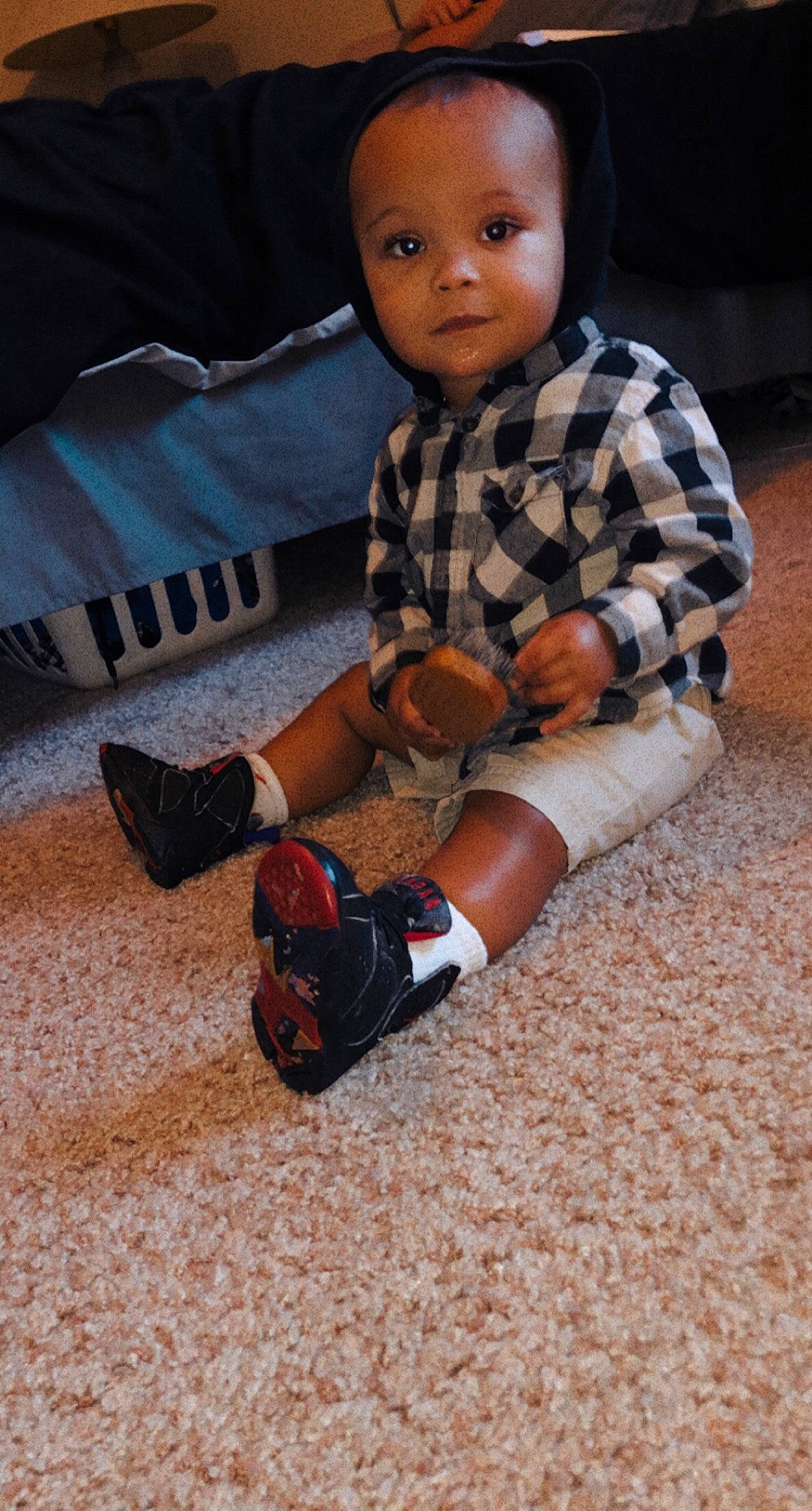 Darius is registered to the contest to win money with this photo: baby_toddler_clothing, child, comfort, flooring, foot, hairstyle, human_leg, joint, knee, pattern, person, plaid, sitting, skin, sleeve, sneakers, sock, tartan, thigh, toddler