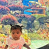 child, toddler, aquarium, fish, coral_reef, underwater, marine_life, sea_life, colorful, portrait, standing, indoors, aquatic, reef, tropical_fish, glass_tank, pink_shirt, pigtails, serious_expression, photography