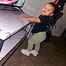 Kiara joined the competition — help win amazing prizes! child, toddler, smiling, happy, standing, stroller, table, indoors, home, playroom, shoes, pants, shirt, chair, television, furniture, carpet, portrait, candid, family