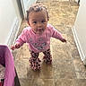 Kiara joined the competition — help win amazing prizes! baby, child, toddler, standing, portrait, face, curly_hair, smiling, curious, pink_shirt, butterfly_pattern, leopard_print, pants, barefoot, hallway, indoor, tiled_floor, playpen, home, photography