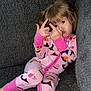 Gabriella joined the competition — help win amazing prizes! child, girl, pajamas, pink, couch, sofa, indoors, face, hands, gesture, expression, hair, brown_hair, long_sleeves, patterned_clothing, home, relaxing, playful, seated, portrait