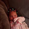baby, child, onesie, cherry_pattern, blanket, couch, hair_clips, flower_clips, smiling, portrait, indoors, cozy, cute, infant, person, face, young_child, soft_fabric, relaxing, comfort