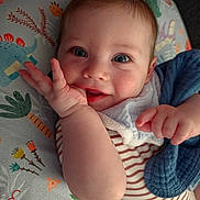 Xavier joined the competition — help win amazing prizes! baby, infant, face, blue_eyes, smile, hand, striped_clothing, blanket, cushion, dinosaur_pattern, cute, child, portrait, closeup, indoors, soft_lighting, happy, young, person, skin