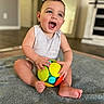 baby, child, smiling, toy, ball, indoor, blanket, happy, sitting, infant, cute, playful, person, floor, casual_clothing, home, young_child, bright_colors, portrait, fun
