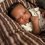 Noble joined the competition — help win amazing prizes! baby, infant, child, blanket, striped_blanket, onesie, star_pattern, sleepwear, face, hand, skin, hair, lying_down, indoors, couch, comfort, curious, expression, closeup, portrait