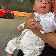 Hugo a rejoint le concours — aidez-le/la à gagner de superbes lots ! adult, baby, car, casual, child, clothing, curious, cute, gray_socks, greenery, hand, holding, infant, outdoor, pacifier, person, red_car, road, trees, white_pants