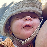 Hugo a rejoint le concours — aidez-le/la à gagner de superbes lots ! baby, baby_clothing, child, closeup, cozy, face, hand, hat, headwear, infant, nature_light, orange_jacket, outdoor, peaceful, person, portrait, resting, skin, sleeping, sunlight