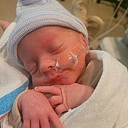 Liam Hughes is registered to the contest to win money with this photo: newborn, baby, sleeping, hat, blanket, hospital, nasal_tube, infant, hand, face, skin, wrapped, cute, peaceful, medical, healthcare, person, closeup, indoors, resting